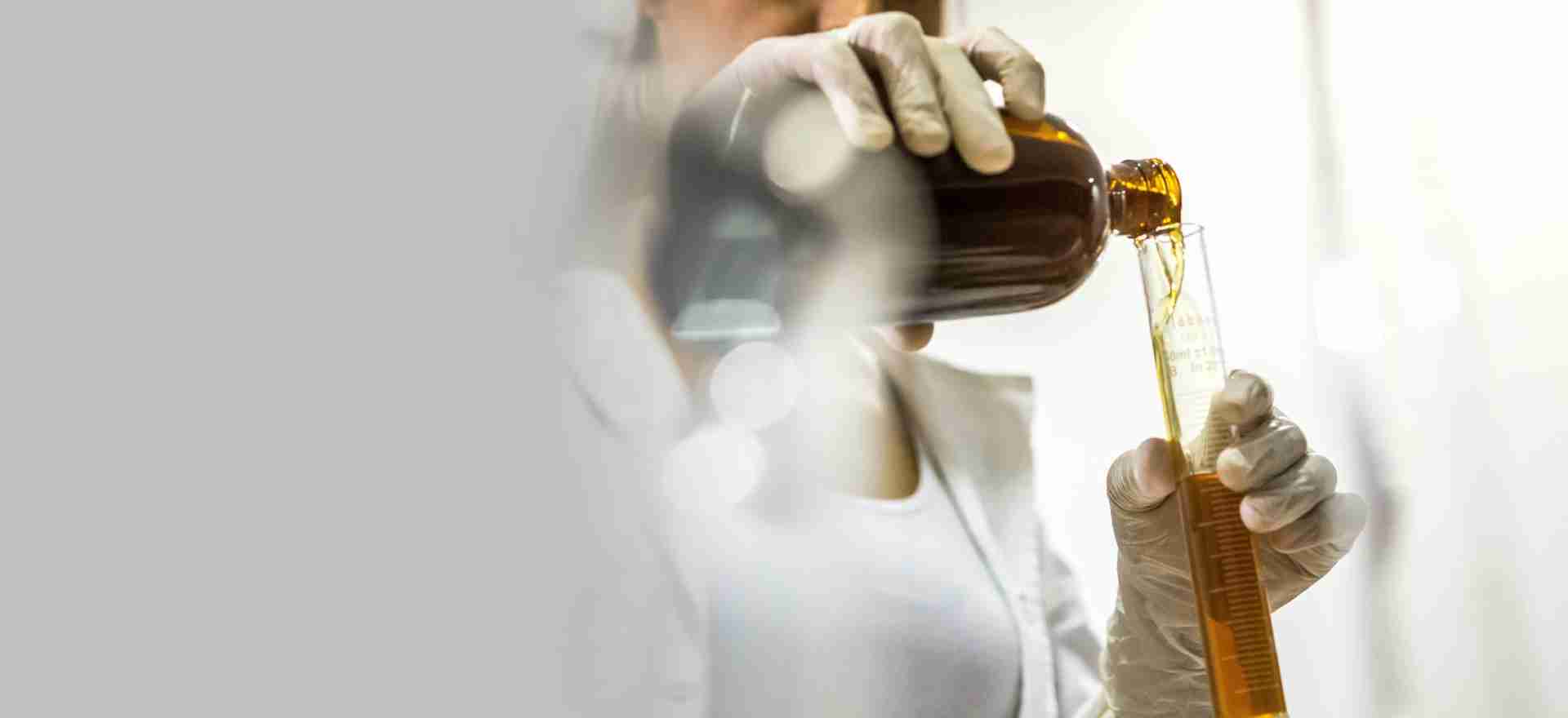 Profesional de laboratorio vertiendo una muestra en una probeta